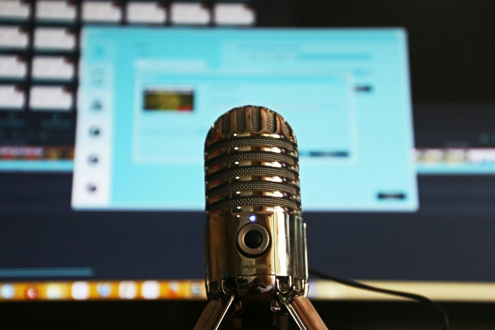 Gold microphone in studio in front of computer screen